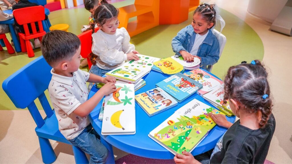 Jonge kinderen lezen samen prentenboeken aan een tafel