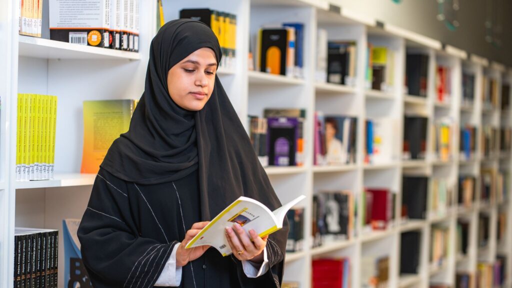 Studente leest een boek in de bibliotheek van het college