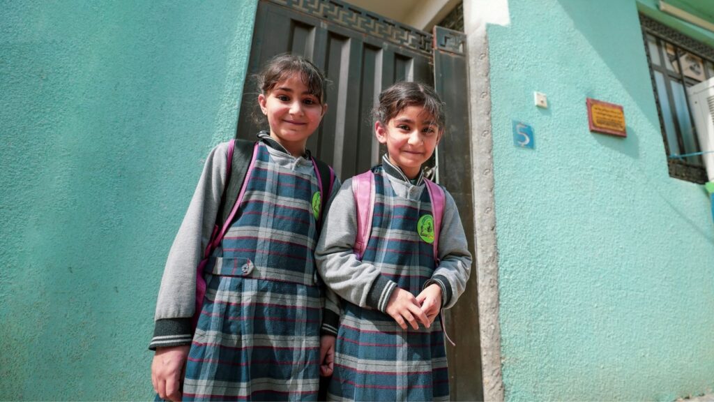 Twee schoolmeisjes in uniform met rugzak voor hun school